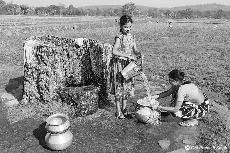 Filtering drinking water using a cloth filter at the Kukuru Daarhi in Jiuri village, jharkhand, India